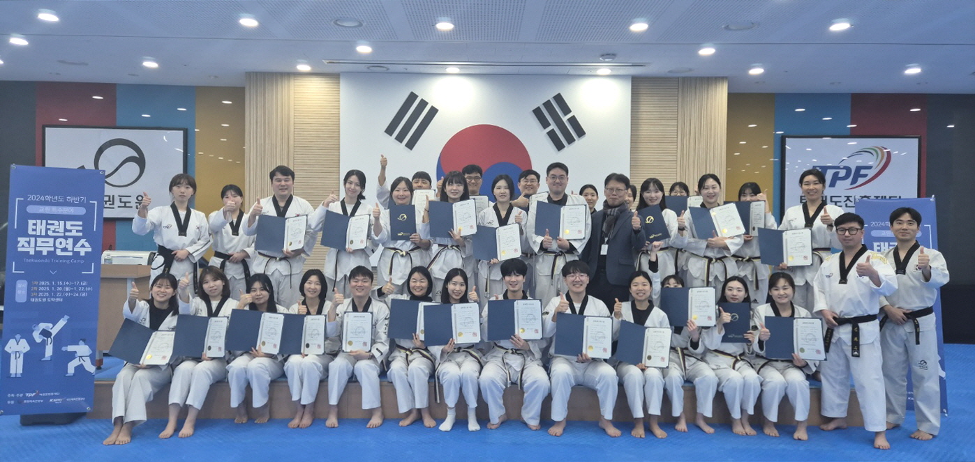 Eine große Gruppe von Taekwondo-Lehrkräften posiert in Doboks und hält Zertifikate vor sich.